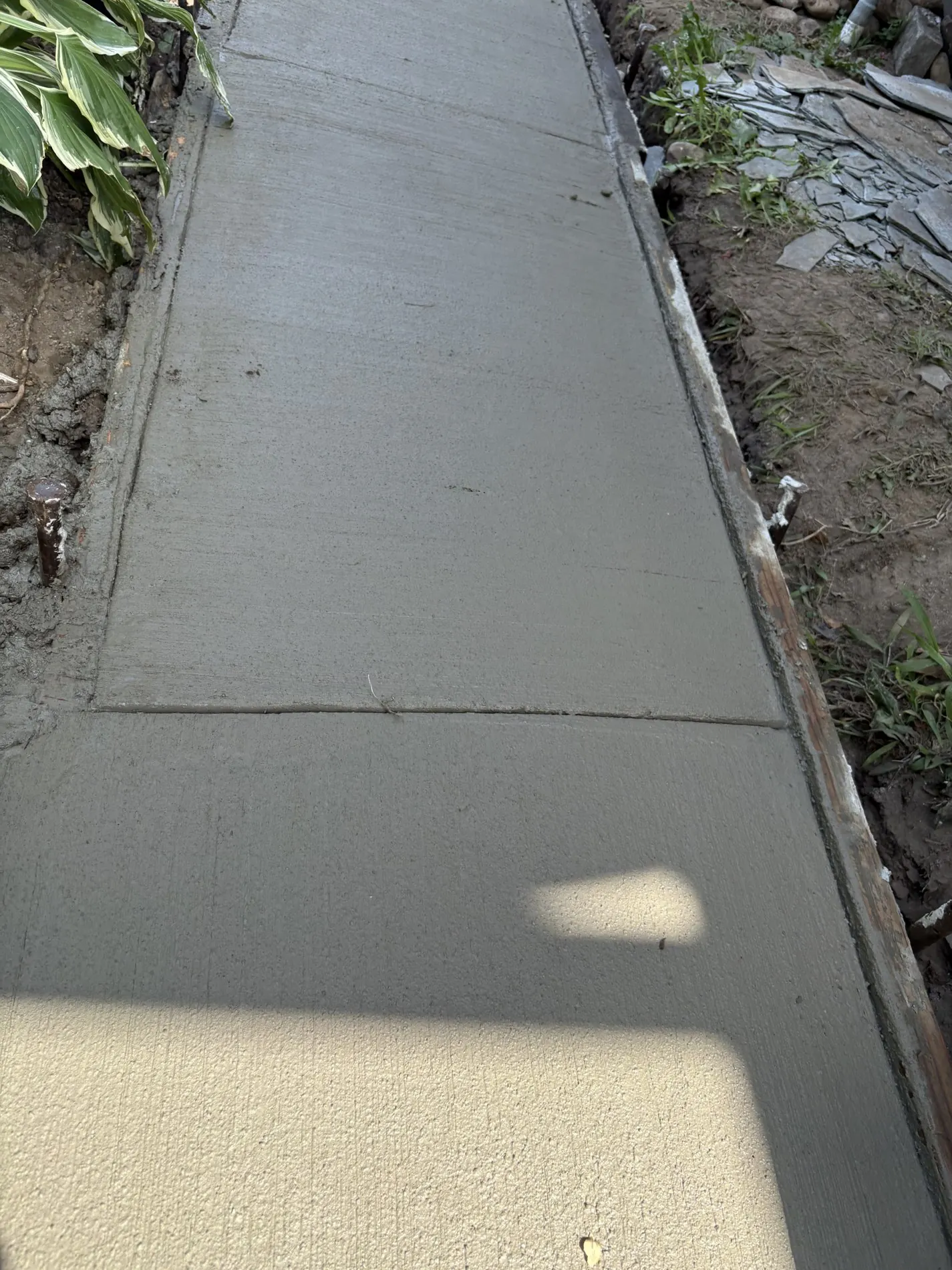 Fresh broom-finished concrete between the planting beds.