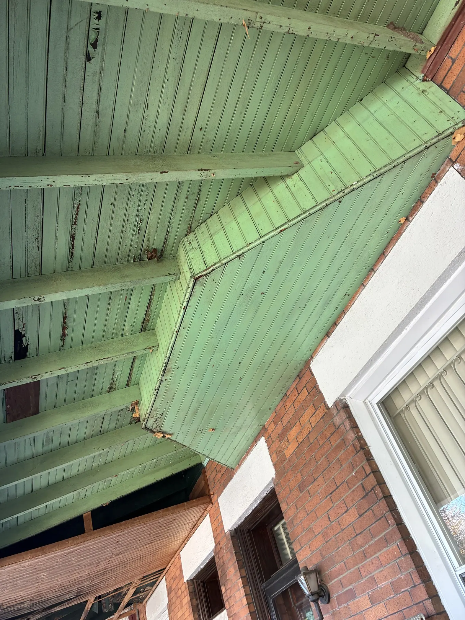Exposed green-painted porch ceiling boards.