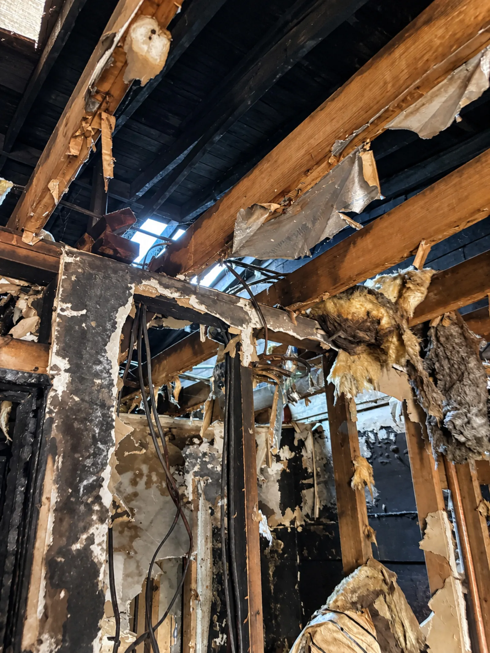Opened interior walls and ceiling with exposed framing and insulation.
